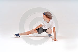 Being physically active. Full length of caucasian teenage boy in sportswear stretching legs, warming up before training