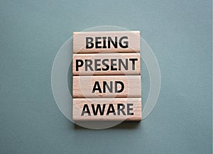 Being Present and Aware symbol. Wooden blocks with words Being Present and Aware. Doctor hand. Beautiful grey green background.