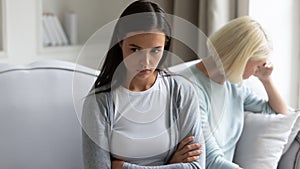 Being in quarrel adult daughter sitting separately from elderly mother