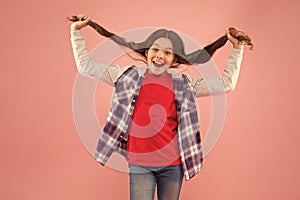 Being such a good girl. Pigtailed little girl pink background. Happy girl hold long hair. Small girl smile in casual photo