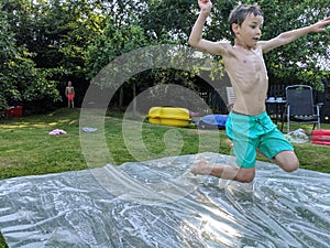 A young boy jumping onto a slip and slide photo