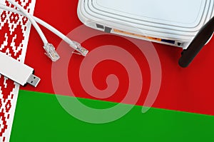 Belarus flag depicted on table with internet rj45 cable, wireless usb wifi adapter and router. Internet connection concept