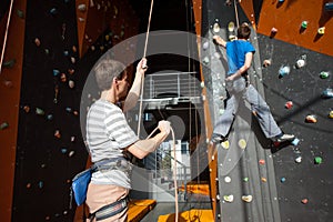 Belayer insuring the climber on rock wall indoors