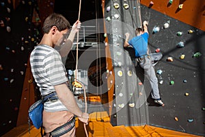 Belayer insuring the climber on rock wall indoors