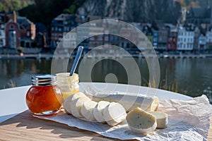 Belgian abbey cheese fagotin in pieces with jam served outdoor with view on Maas river and center of Dinant, Wallonia, Belgium