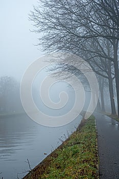 Belgian countryside canal with fog and reflection at sunrise in wintertime