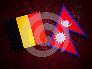 Belgian flag with Nepali flag on a tree stump isolated