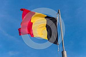 Belgian flag waving against blue sky