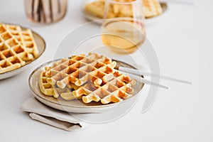 Belgian waffles with banana and condensed milk on white table