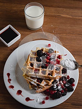 Belgian waffles with berries. milk. Syrup. Wooden table.