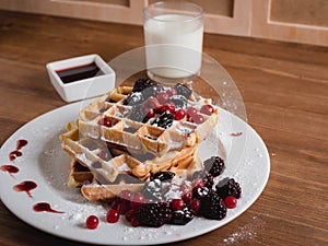 Belgian waffles with berries. milk. Syrup. Wooden table.
