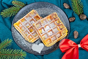 Belgian waffles on a black plate sprinkled. Christmas and New Year mood. Top view