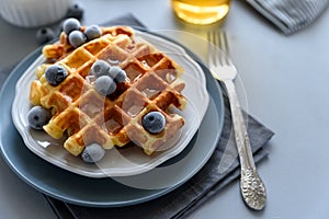 Belgian waffles with blueberries and honey on gray wooden background. Homemade healthy breakfast. Selective focus