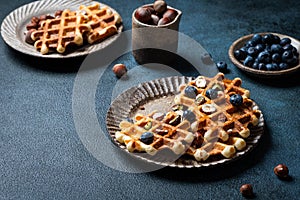 Belgian waffles with honey and fresh berries blueberry and hazelnut on dark background. Delicious dessert. Copy space