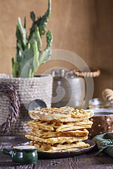 Belgian waffles served with honey, cream and sai on a wooden background. Rustic style.