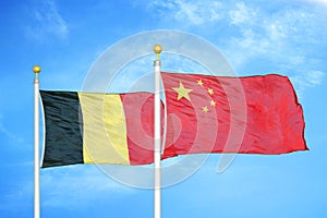 Belgium and China two flags on flagpoles and blue cloudy sky