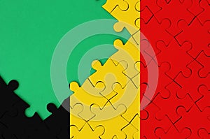 Belgium flag is depicted on a completed jigsaw puzzle with free green copy space on the left side
