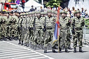 Rows of military troop marching on streets during sunny summer day