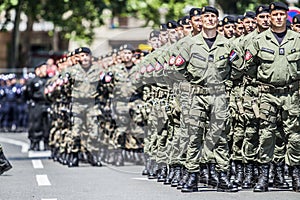 Rows of military troop marching on streets during sunny summer day