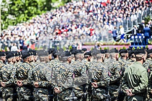 Rows of military troop marching on streets during sunny summer day