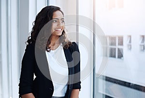 Believe in all the potential you have. a young businesswoman looking out the window in an office.