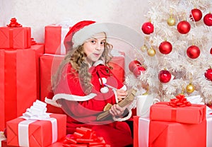 Believe in miracle. Girl little cute child hold pen and paper near christmas tree. Wish list. Letter for santa. Kid