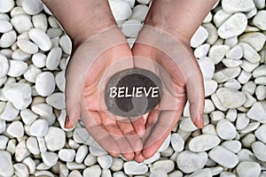 Believe word in stone on hand photo