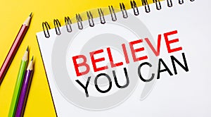Believe you can on a white notepad with pencils on a yellow background. Business concept