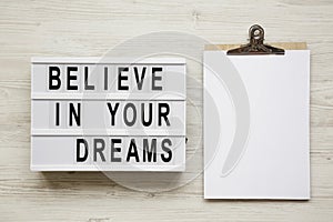 `Believe in your dreams` word on modern board, noticeboard over white wooden background, top view. Flat lay, from above