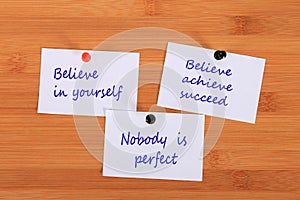 Believe in yourself. Believe achieve succeed. Nobody is perfect. Note pin on the bulletin board.