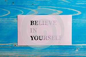 Believe in yourself sign fading into a Be you message written on pink paper