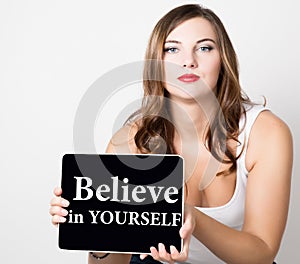 Believe in yourself written on virtual screen. beautiful woman with bare shoulders holding pc tablet. technology