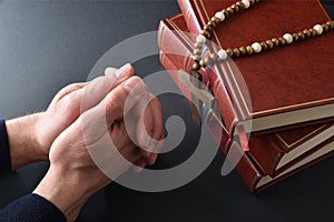 Believer praying over black table with books and cross