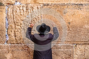 Believing pray near the wall of crying in a black hat