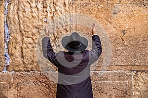 Believing pray near the wall of crying in a black hat