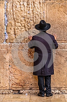 Believing pray near the wall of crying in a black hat