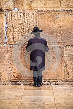 Believing pray near the wall of crying in a black hat