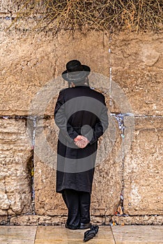 Believing pray near the wall of crying in a black hat