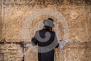 Believing pray near the wall of crying in a black hat