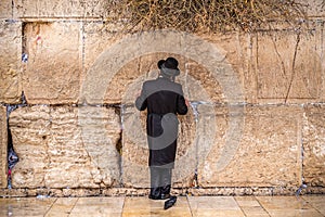 Believing pray near the wall of crying in a black hat