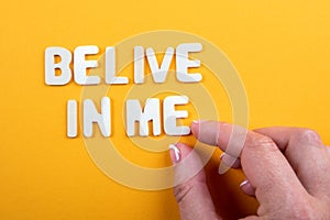 Belive In Me. White wooden letters with text on a yellow background