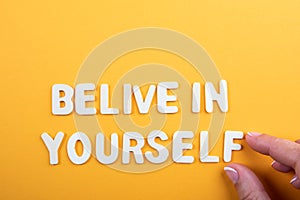 Belive in Yourself. Letters of the alphabet and a woman& x27;s hand on a yellow background