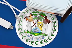 Belize flag depicted on table with internet rj45 cable, wireless usb wifi adapter and router. Internet connection concept