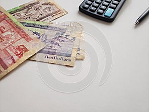belizean banknotes of different denominations, calculator and black pen on white background photo