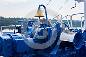 Bell, capstan and other mechanisms, painted blue, on the foredeck of the river ship, close-up