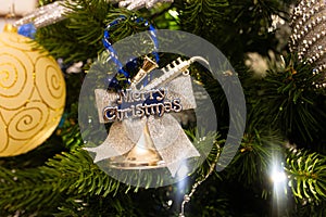 Bell christmas decoration with the Merry Christmas message written on it hanging on the christmas tree