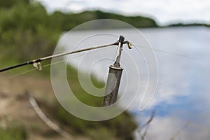 Bell on a fishing spinning rod. Fishing feeder on the river. Blurred background