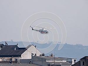 Bell 412 helicopter of the Government of Spain flying over the buildings of the city of Monforte during the fire season in Galicia