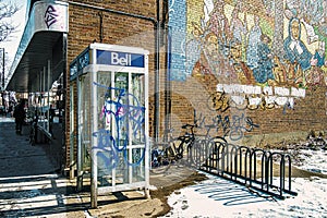 Bell outside phone booth serving for grafiti beside a mural