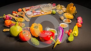 Bell pepper and different kinds of vegetables on black table.